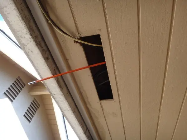 Attic access opening used to route CAT6 wiring for residential security camera installation in Lakewood.