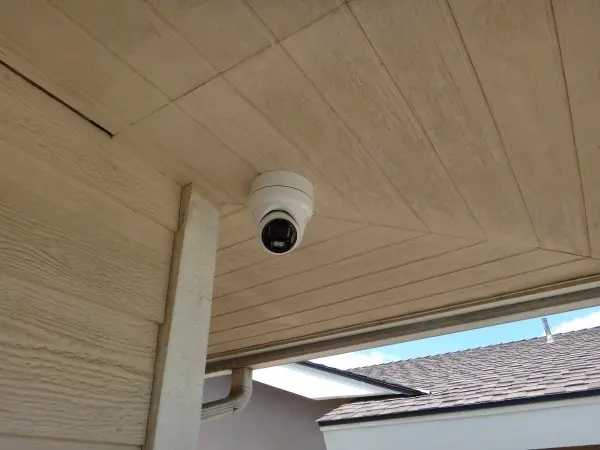 Dome security camera installed under roof soffit providing backyard surveillance coverage for a residential property