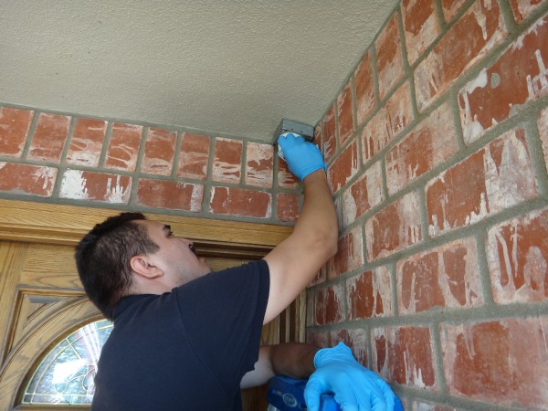 Technician replacing connector and servicing front door security camera during maintenance visit in Long Beach CA