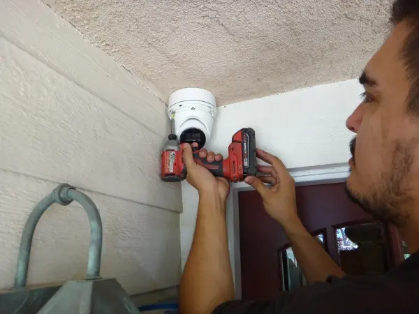 Technician installing outdoor security camera near front entrance during residential CCTV installation in Lakewood.