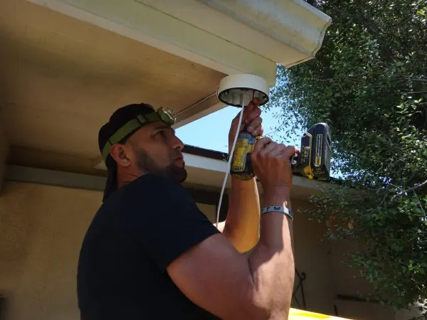 Security camera installation technician mounting outdoor surveillance equipment on residential property