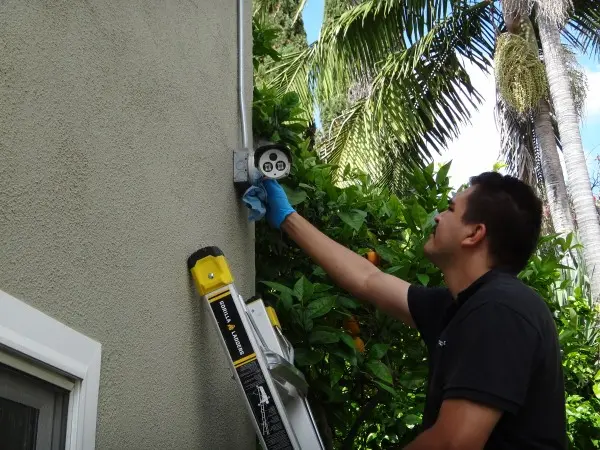 Technician cleaning outdoor security camera lens during maintenance service