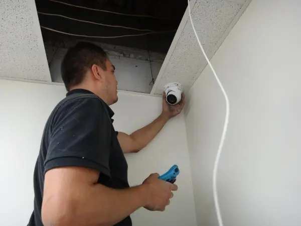 Technician installing a commercial security camera inside a warehouse office in La Habra CA