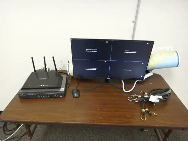 Security camera system setup featuring an NVR, wireless network equipment, and monitor during testing and configuration.