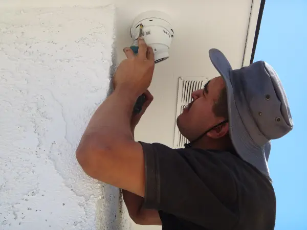 Technician installing an outdoor security camera on a residential home in Lakewood, CA.