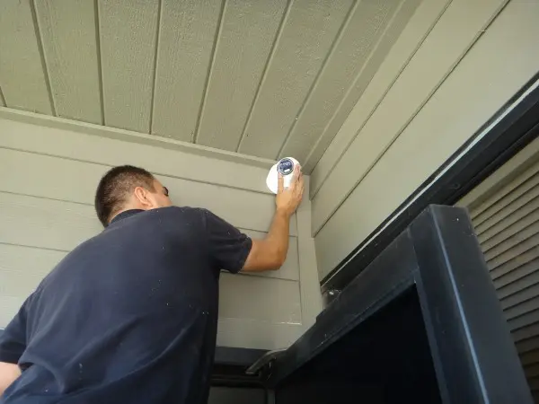 Technician installing a commercial security camera above a warehouse entrance