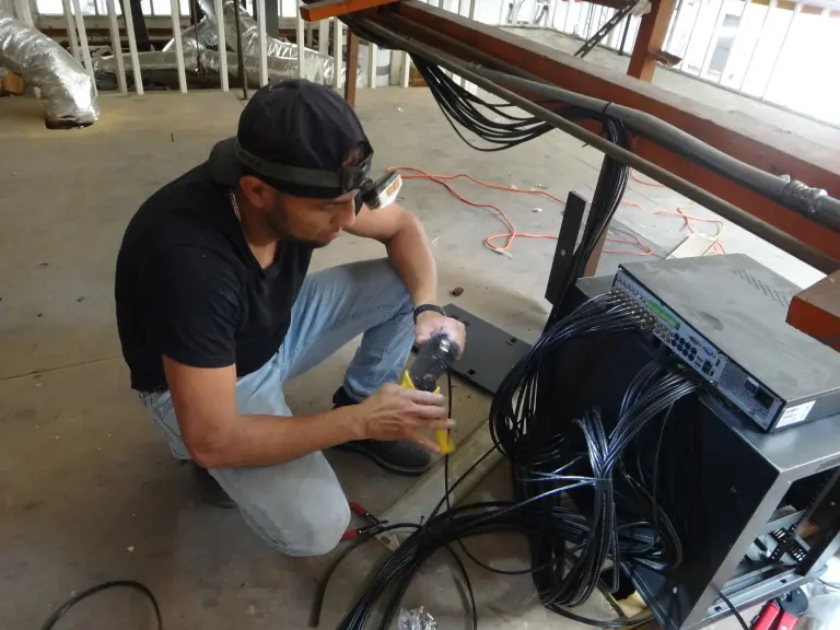 Security camera installer connecting surveillance camera cables to a DVR system during a commercial security camera installation