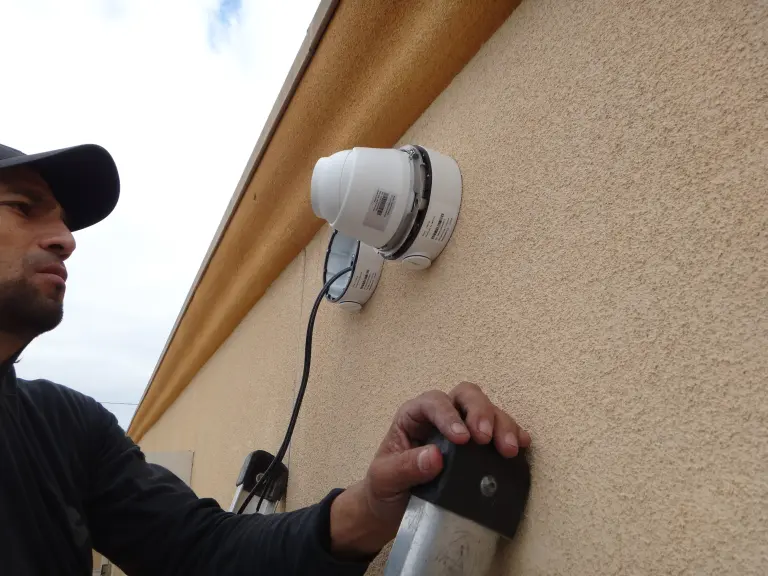 Technician finishing installation of security camera on commercial property in Pico Rivera CA