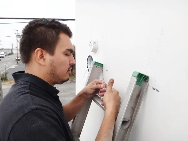 Protection4Less technician preparing a Cat6 Ethernet cable for a commercial security camera installation in Santa Fe Springs, CA.