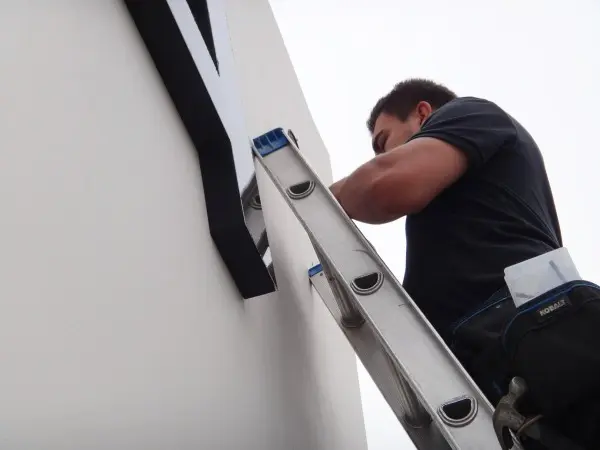 Protection4Less technician installing a commercial security camera system on a business building in Santa Fe Springs, CA.
