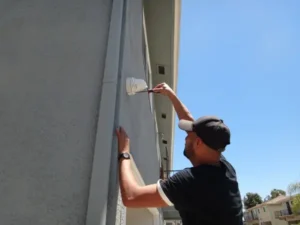 Technician installing an outdoor security camera near the garage with protected conduit wiring during a residential security camera installation