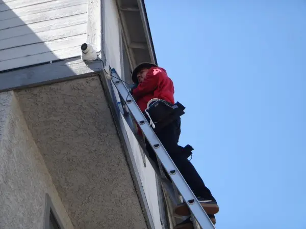 Protection4Less technician installing a 4K security camera near the roofline of a home in Azusa, CA
