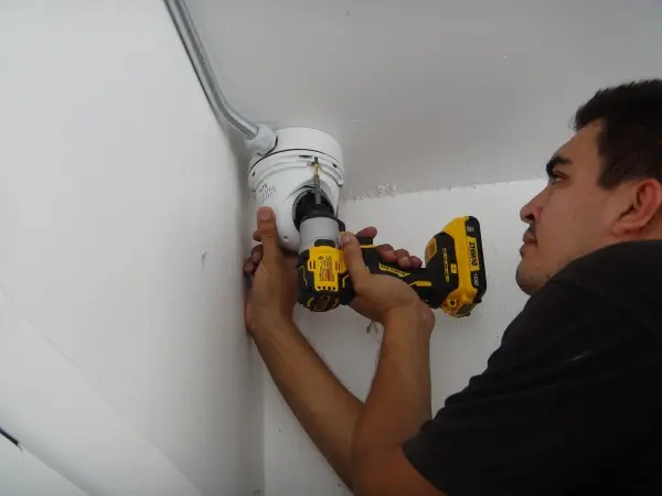 Technician installing an outdoor security camera with protected conduit wiring during a residential security camera installation in Rowland Heights CA.