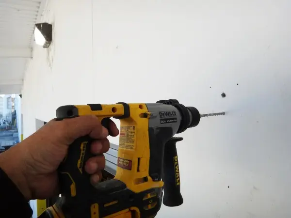 Preparing the wall for a security camera junction box during a commercial warehouse security camera installation in Paramount