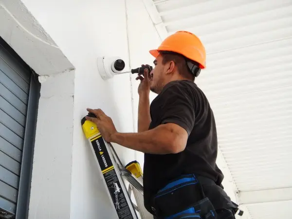 echnician adjusting a commercial security camera to provide complete coverage of a warehouse loading dock in Paramount.
