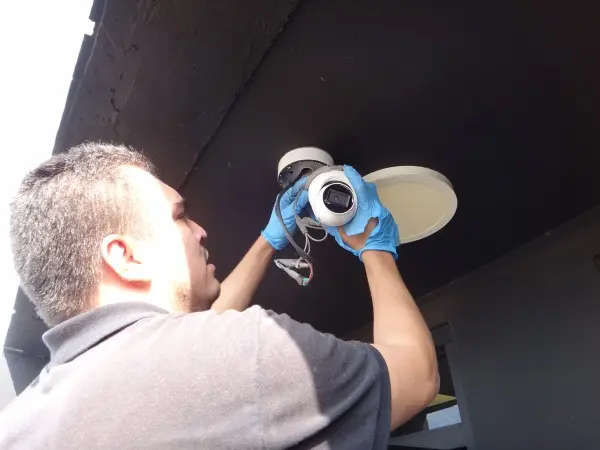 Technician installing security camera at apartment building garage in South Gate, CA