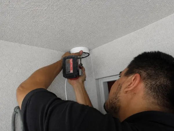 Technician installing security camera on apartment building in South Gate, CA