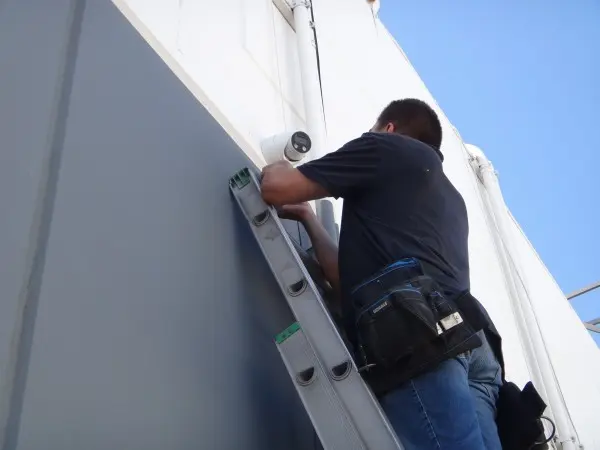 Technician installing an outdoor security camera at a Gardena warehouse
