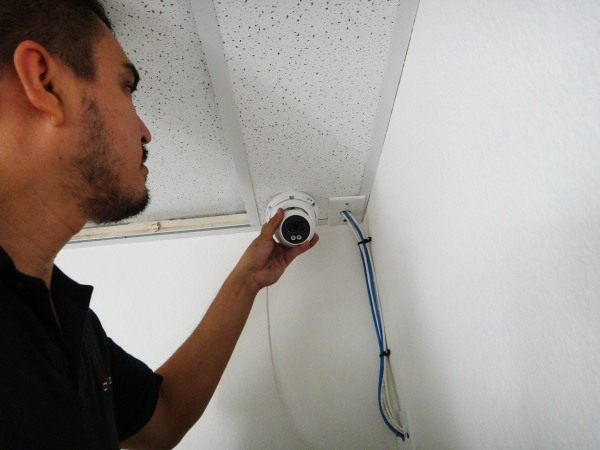 Technician installing a security camera inside a Gardena warehouse